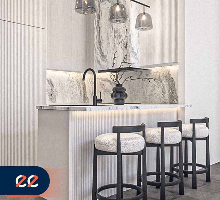 تصميم داخلي لمطبخ حديث بنمط أنيق مع جزيرة مطبخ من الرخام وأضواء معلقة عصرية وكراسي بار سوداء مع مسند أبيض، يعكس مشاريع إيلفينز في التصميم الداخلي الفاخر.