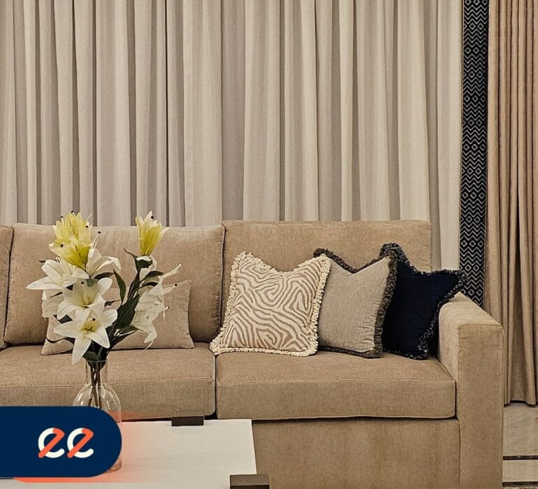 تصميم داخلي حديث لغرفة معيشة أنيقة من مشاريع ايلفينز مع أريكة ناعمة ووسائد مزخرفة وستائر منسقة تتناغم مع ديكور فاخر يعكس الجودة والتميز.