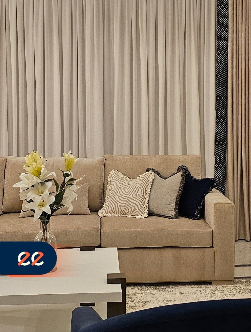 تصميم داخلي حديث لغرفة معيشة أنيقة من مشاريع ايلفينز مع أريكة ناعمة ووسائد مزخرفة وستائر منسقة تتناغم مع ديكور فاخر يعكس الجودة والتميز.