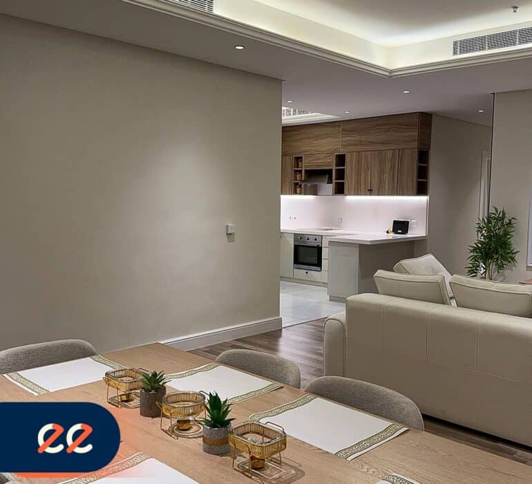 ديكور داخلي حديث وراقي لمنزل فخم مع جلسة عائلية أنيقة ومطبخ مفتوح على غرفة الطعام في مشروع إيلفينز، يعكس تصاميم معمارية مميزة وإضاءة متجددة لخلق أجواء دافئة ومريحة.