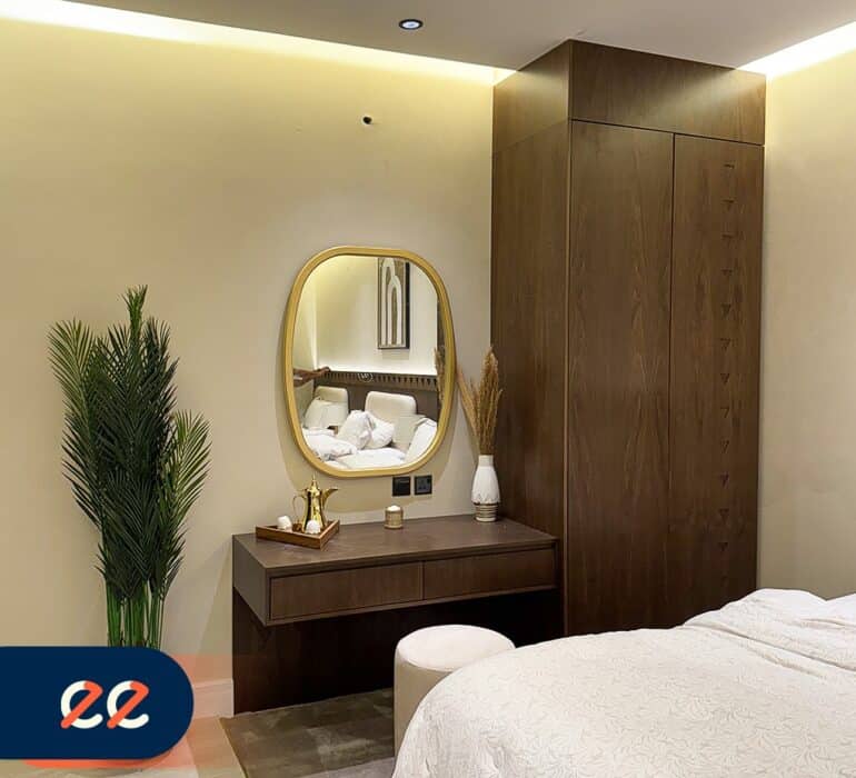 تصویر لغت أسود، داخلي لغرفة نوم فاخرة مع تصميم حديث وأضاءة هادئة وأثاث أنيق وأمام مرآة دائرية، ديكور عصري يتماشى مع مشاريع ايلفينز.