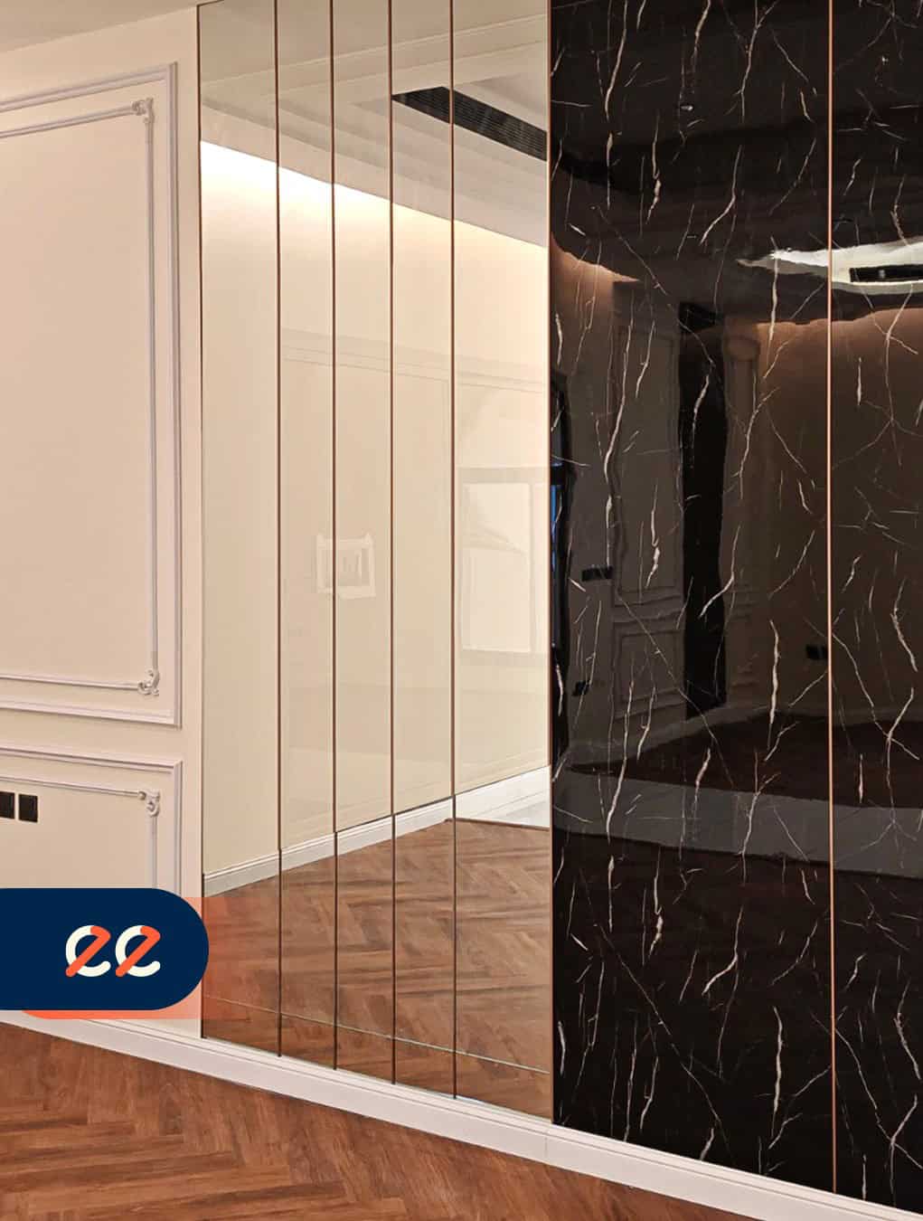 تصريح الصورة: مرآة فاخرة بتصميم أنيق وحديث تضيف لمسة من الفخامة والراحة للمساحات الداخلية، مع إطار ذهبي رفيع وواجهة سوداء مرقّعة بتدرجات مميزة، مثال على مشاريع إيلفينز.